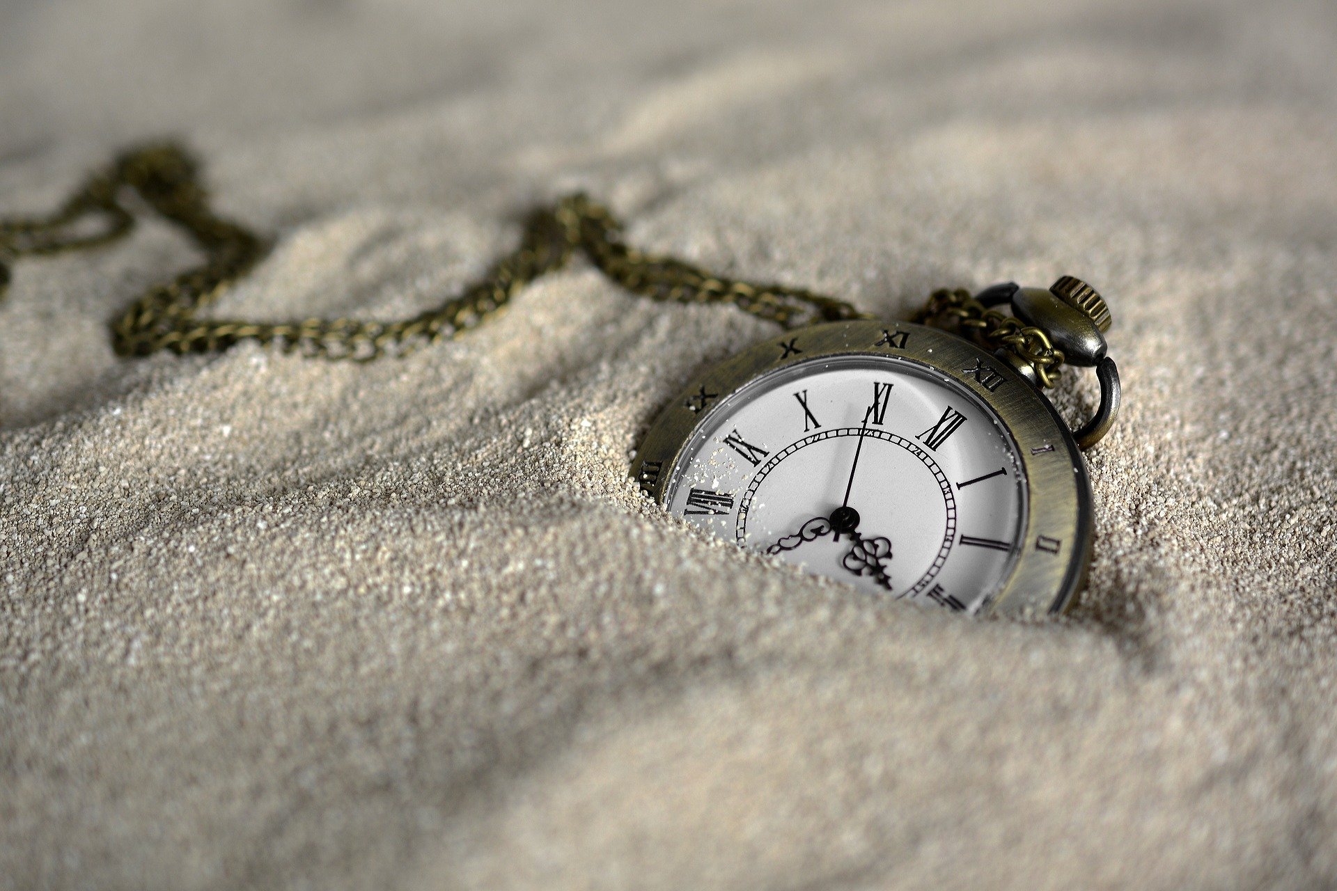 A time piece half covered in sand